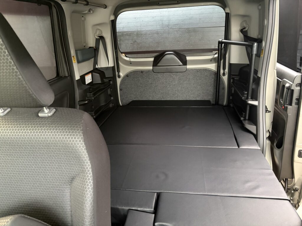 助手席側から見たスペーシアベースのフルフラットベッド展開状態と足元スペースの隙間埋め