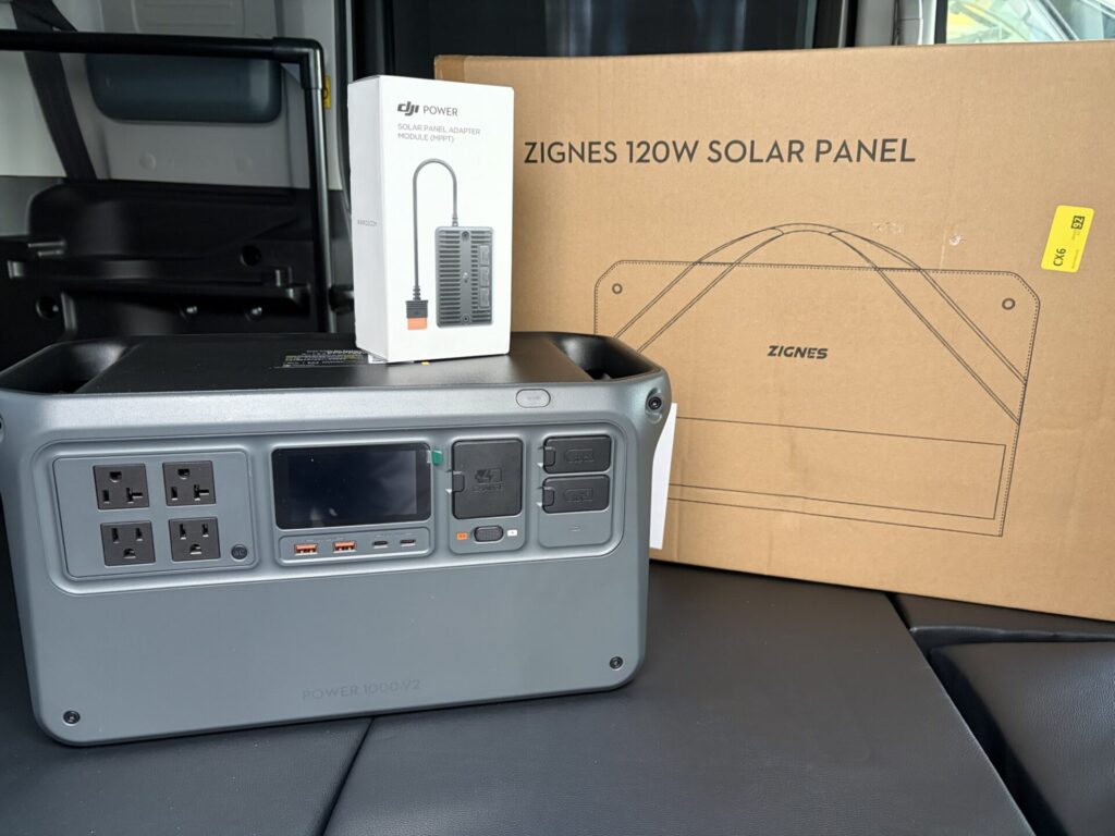 ペーシアベースの車内で購入した120Wソーラーパネルとアダプターを確認する様子