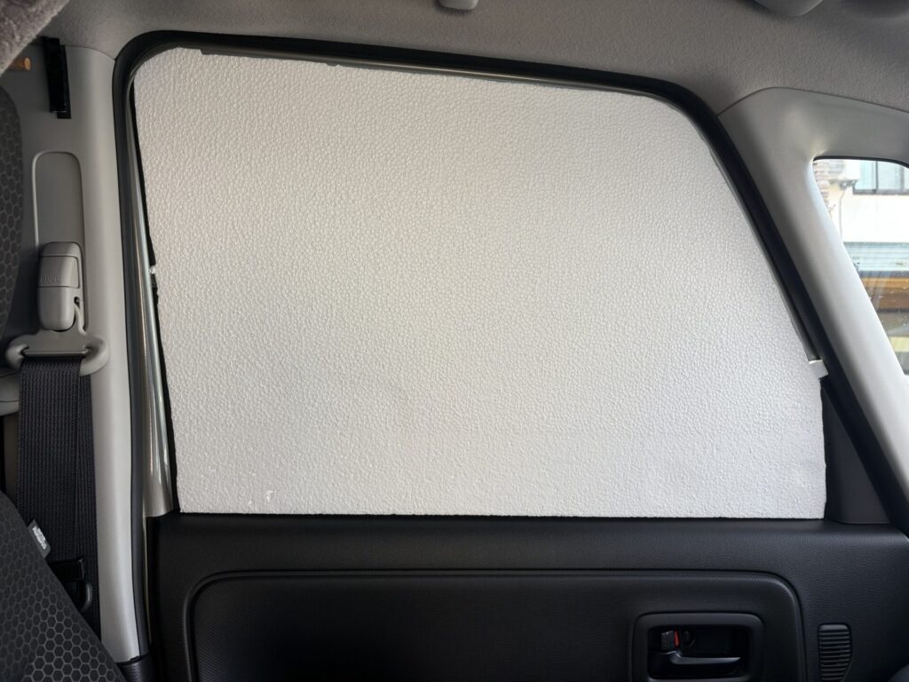 スペーシアベースの助手席の窓に、型取り用の白い発泡スチロールを当ててサイズを確認している様子