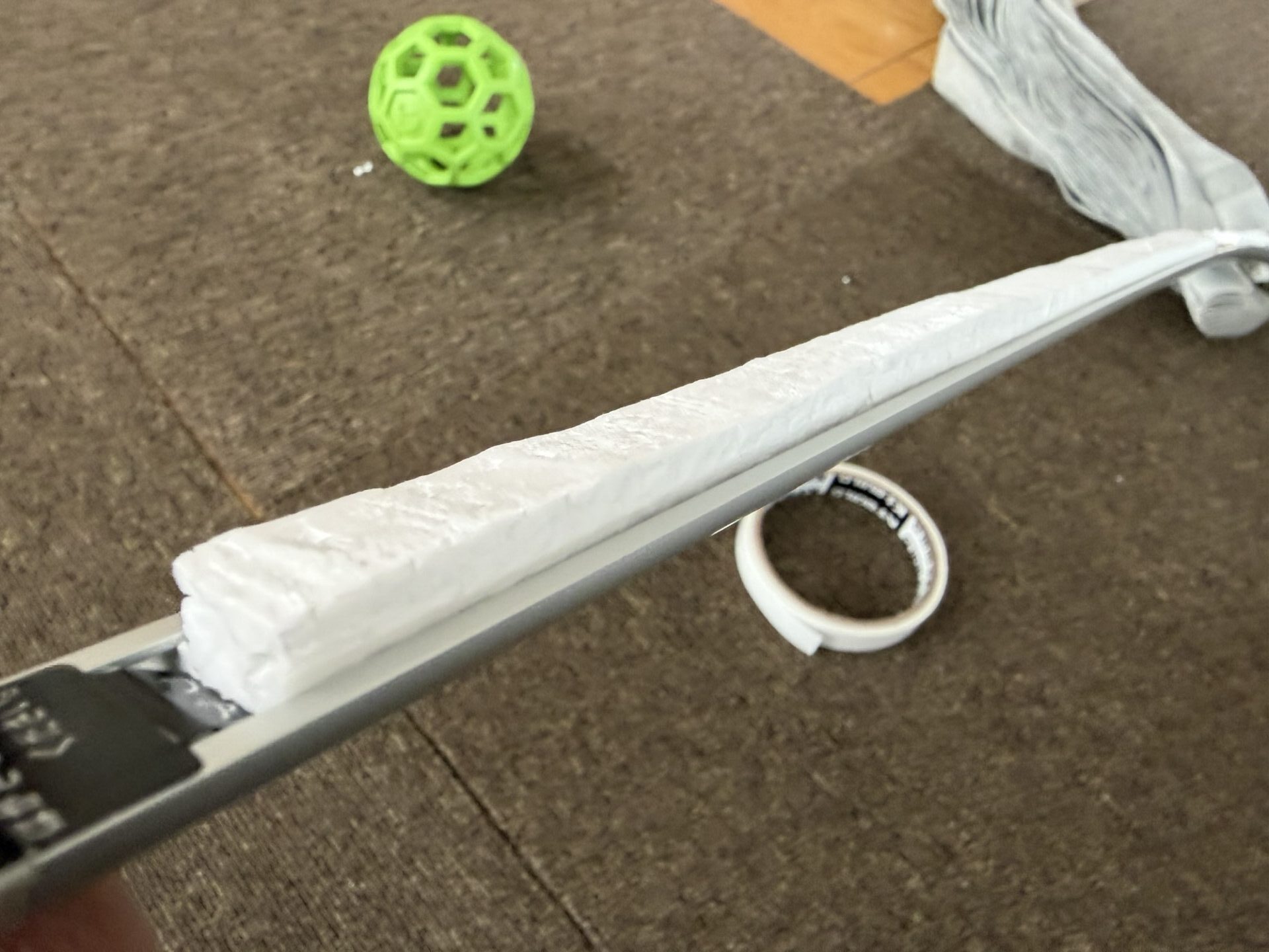 カーテンレールの裏側の凹み部分に、白い発泡スチロールのような端材を埋め込んで平らにしている様子