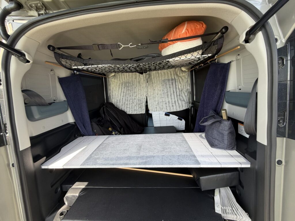 スペーシアベースの車内後方の全景。自作のテーブルと、天井に設置されたルーフネット収納が見える。