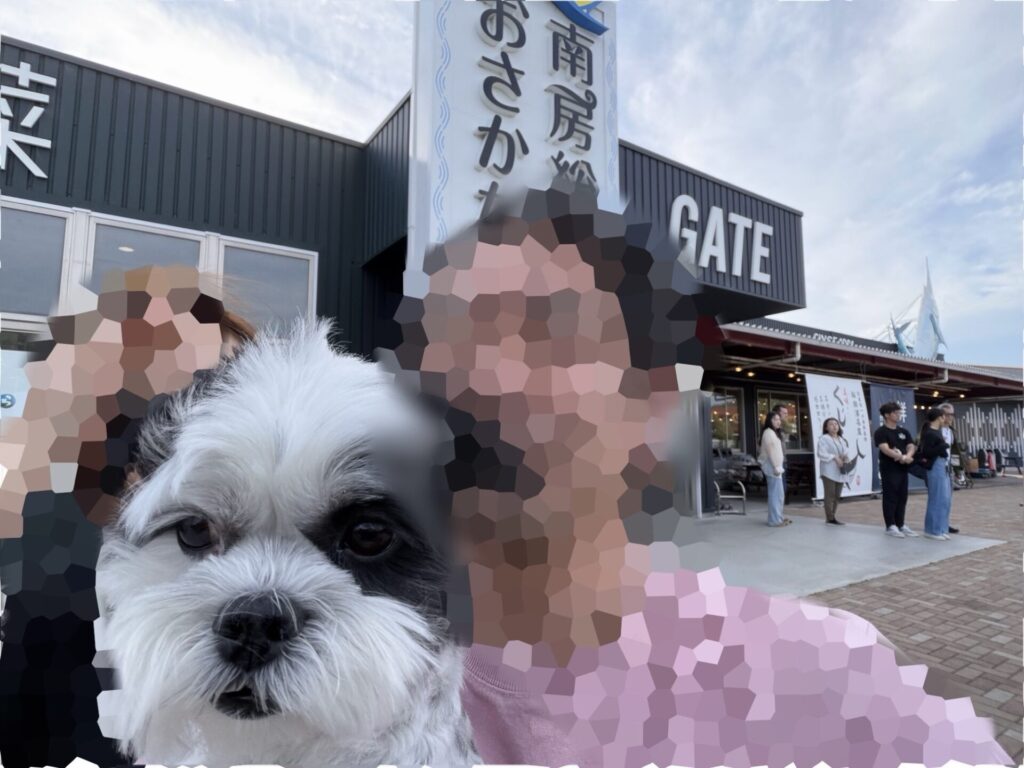 房総の駅 富浦の建物をバックに、愛犬おーちゃんを抱っこして記念撮影をするパパとママ