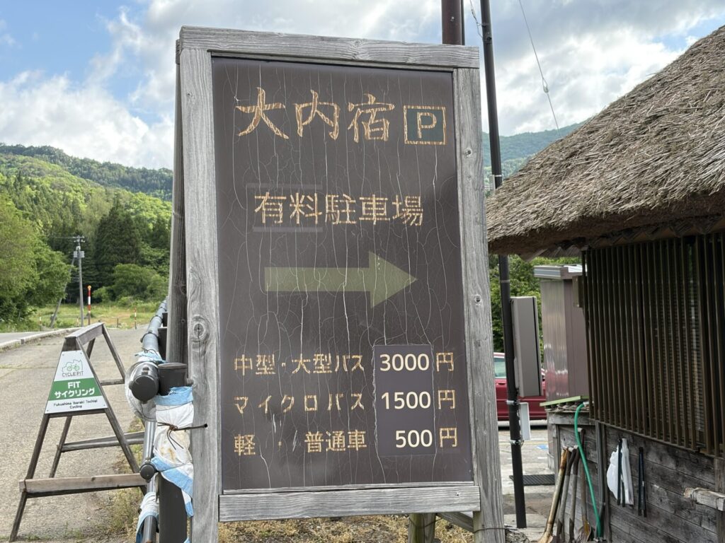 「普通車 500円」と書かれた大内宿駐車場の料金表と利用案内看板